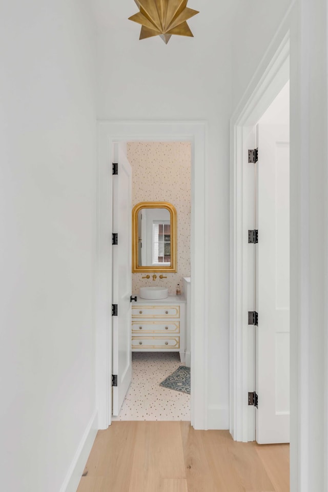 corridor with hardwood / wood-style floors and sink