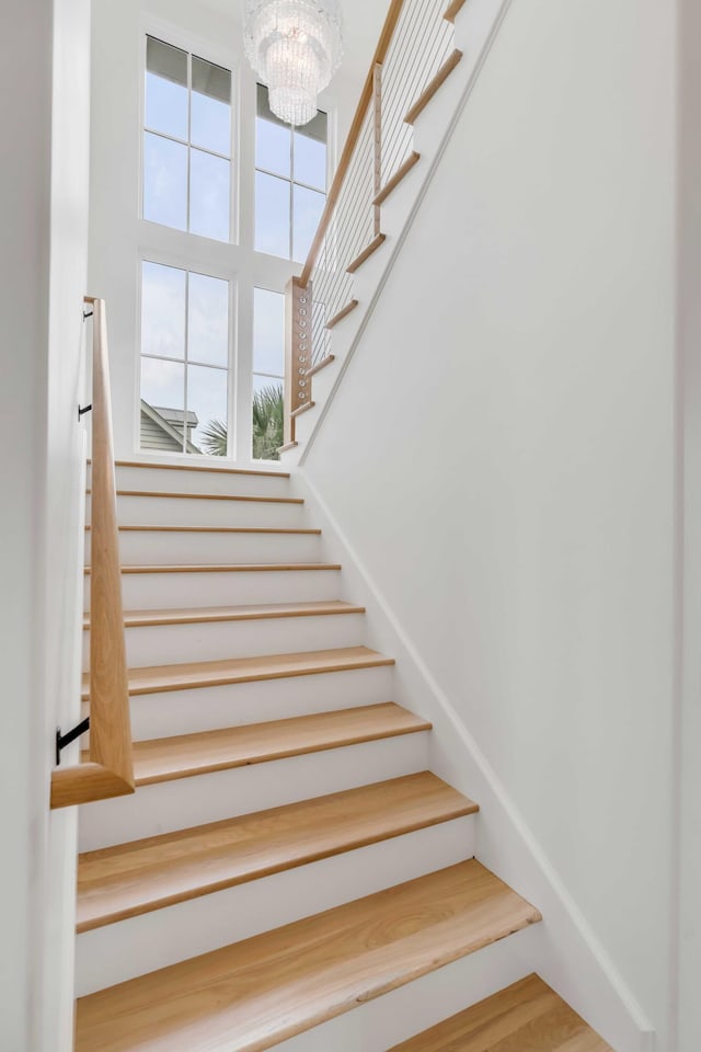 staircase with hardwood / wood-style floors and a notable chandelier