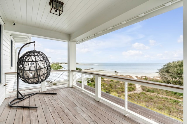 wooden terrace featuring a water view and a beach view