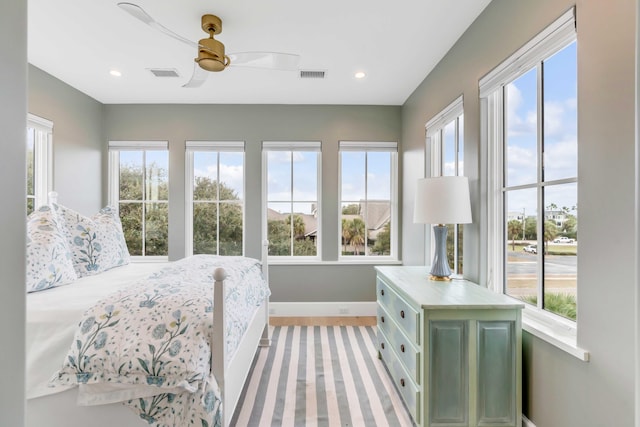 bedroom featuring ceiling fan, light wood-type flooring, and multiple windows