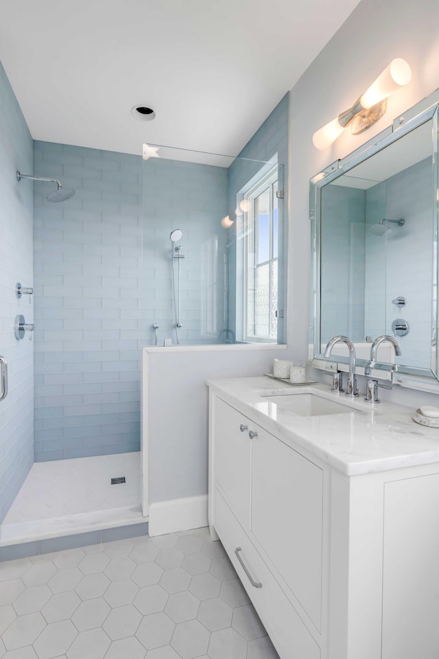 bathroom with a tile shower, vanity, and tile patterned floors