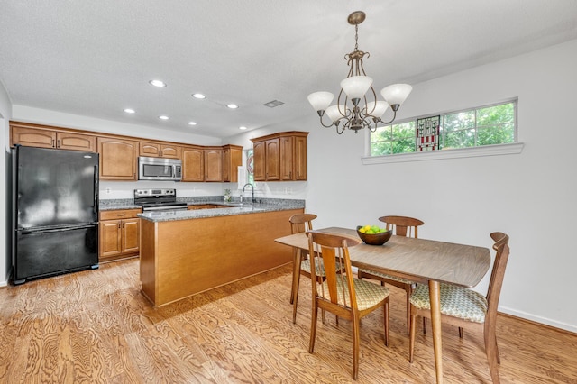 kitchen featuring brown cabinets, light wood-style floors, stainless steel appliances, recessed lighting, and a peninsula