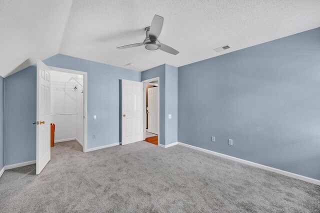 unfurnished bedroom featuring carpet floors, a textured ceiling, a ceiling fan, baseboards, and visible vents