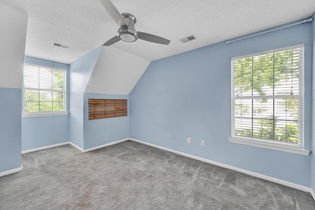 additional living space with a ceiling fan, carpet flooring, a textured ceiling, and visible vents