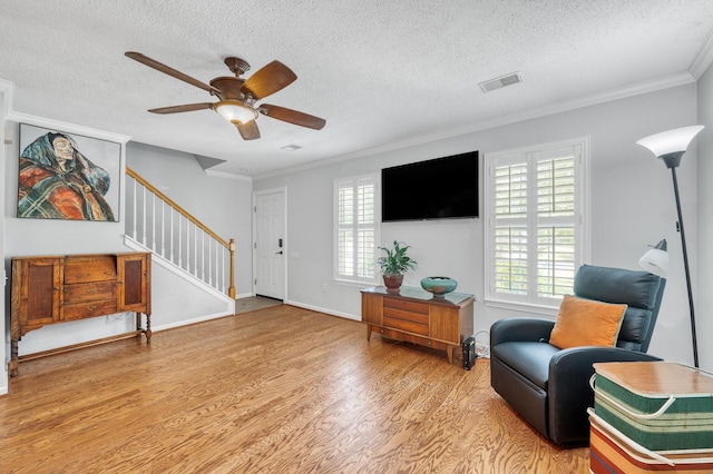 interior space featuring crown molding, a textured ceiling, visible vents, and wood finished floors
