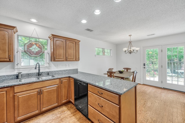 kitchen featuring visible vents, a peninsula, light wood-style floors, black dishwasher, and a sink