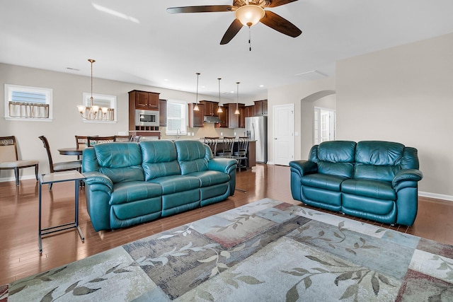 living room with ceiling fan with notable chandelier and dark wood-type flooring