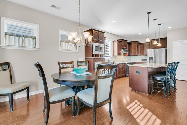 dining room with a notable chandelier and light wood-type flooring