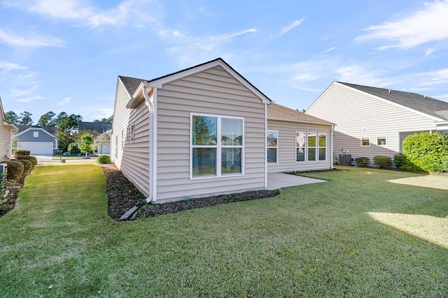 rear view of house featuring central AC and a yard