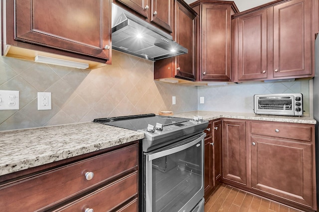 kitchen with light stone countertops, backsplash, and stainless steel electric range