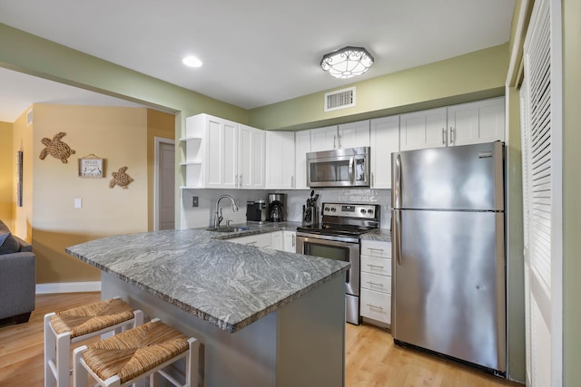 1605 Live Oak Park, Seabrook Island, SC 29455 - kitchen featuring appliances with stainless steel finishes, a sink, white cabinetry, open shelves, and a peninsula