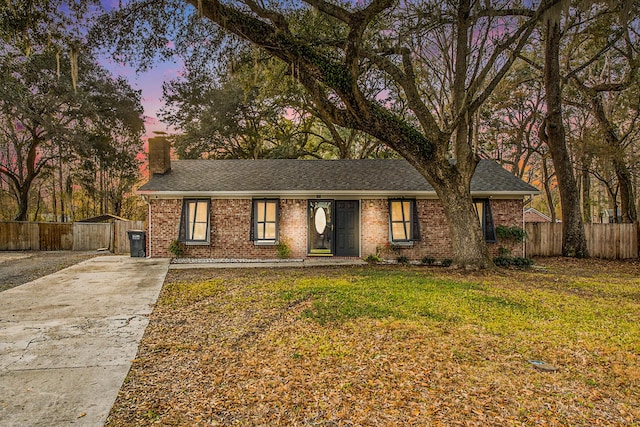 single story home with a storage shed and a yard