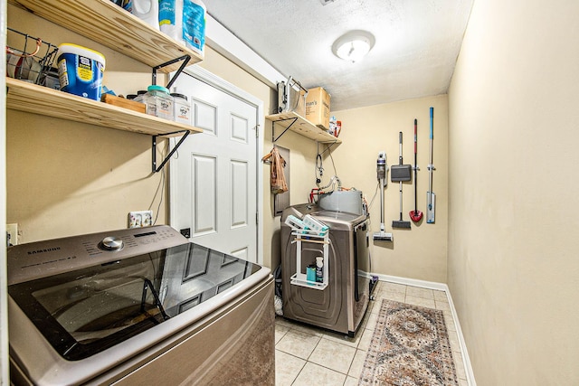 washroom featuring light tile patterned flooring, washer and dryer, and a textured ceiling