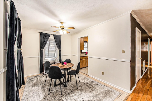 dining area featuring light tile patterned flooring, sink, crown molding, a textured ceiling, and ceiling fan