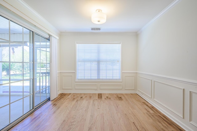 unfurnished room featuring a decorative wall, light wood-style floors, visible vents, and ornamental molding