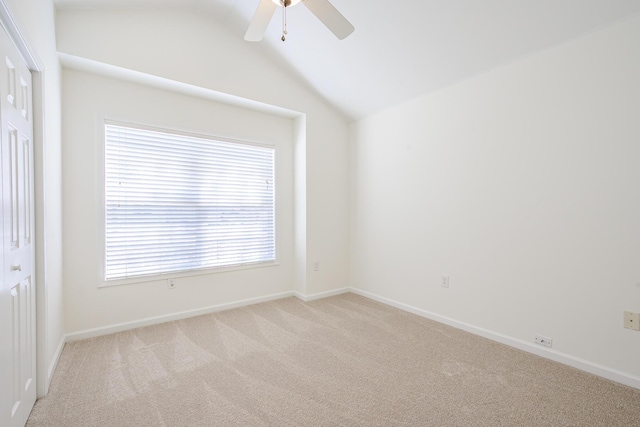 empty room featuring baseboards, light carpet, a ceiling fan, and vaulted ceiling