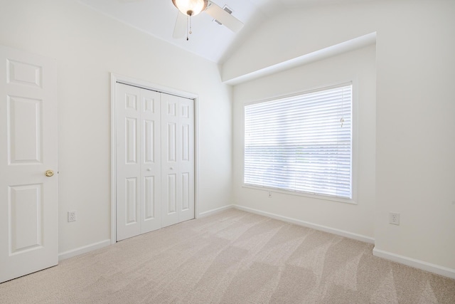 unfurnished bedroom with a closet, lofted ceiling, carpet, and baseboards