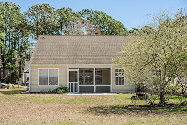 rear view of property with a fire pit, a sunroom, a yard, and a shingled roof