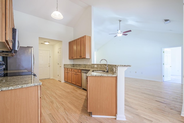 kitchen with light stone counters, light wood-style flooring, appliances with stainless steel finishes, a peninsula, and a sink