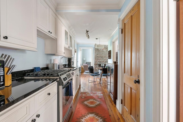 162 Spring St, Charleston, SC 29403 - kitchen featuring stainless steel range with gas cooktop, dark countertops, light wood-style flooring, white cabinets, and crown molding