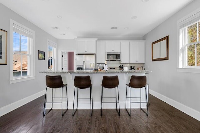 162 Spring St, Charleston, SC 29403 - kitchen featuring stainless steel appliances, baseboards, white cabinets, a breakfast bar area, and dark wood finished floors