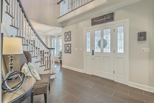 foyer featuring crown molding, dark tile patterned flooring, and a high ceiling