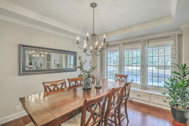 dining space with dark hardwood / wood-style flooring, crown molding, a tray ceiling, and a chandelier