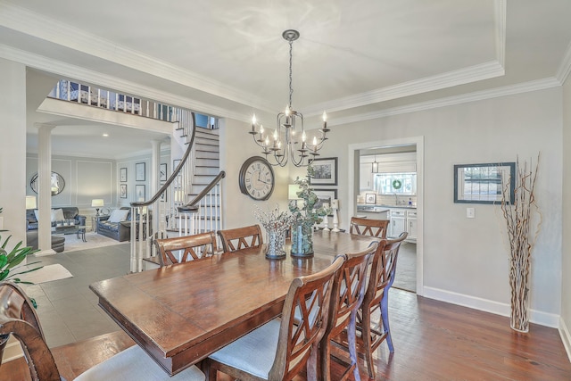 dining space with crown molding, a chandelier, hardwood / wood-style floors, and ornate columns