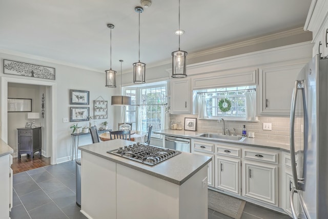 kitchen with sink, white cabinetry, hanging light fixtures, stainless steel appliances, and a kitchen island