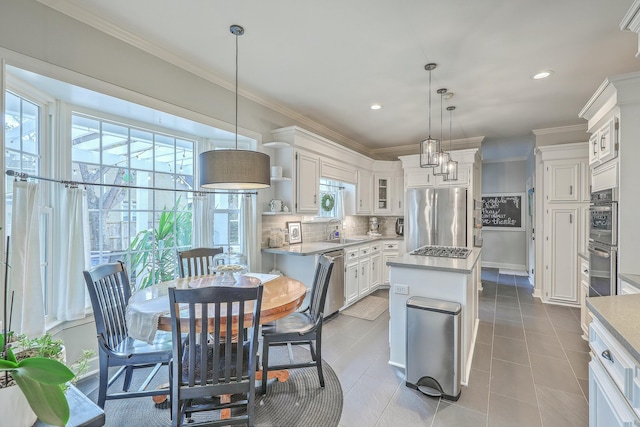 kitchen featuring sink, decorative light fixtures, appliances with stainless steel finishes, a kitchen island, and white cabinets