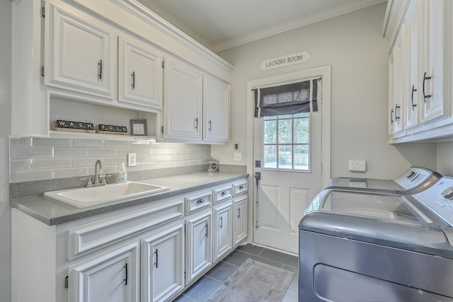 clothes washing area featuring separate washer and dryer, sink, dark tile patterned flooring, cabinets, and ornamental molding