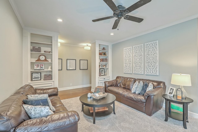 living room featuring built in features, ornamental molding, ceiling fan, and light wood-type flooring