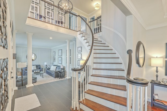 stairway featuring ornate columns, ornamental molding, and a high ceiling