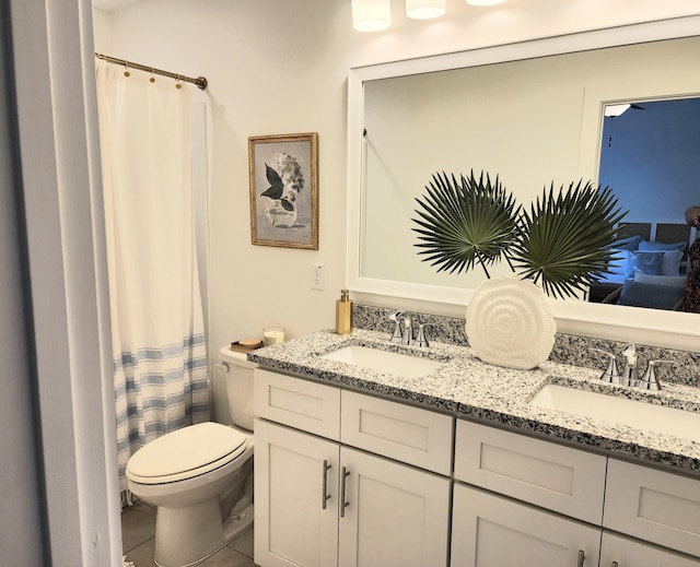 bathroom with a sink, toilet, and double vanity