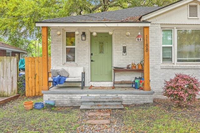 1188 Camden St, North Charleston, SC 29405 - doorway to property featuring roof with shingles, fence, and brick siding