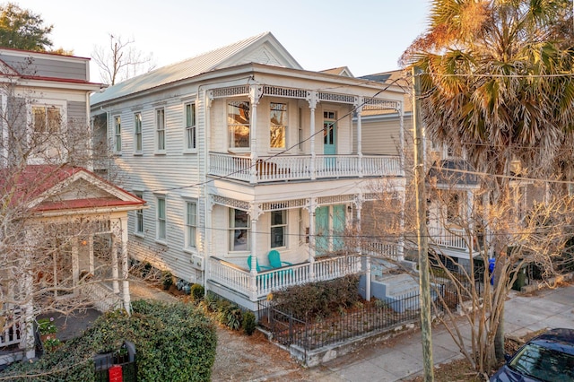 rear view of property with a porch and a balcony