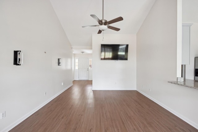 unfurnished living room with a ceiling fan, high vaulted ceiling, wood finished floors, and baseboards