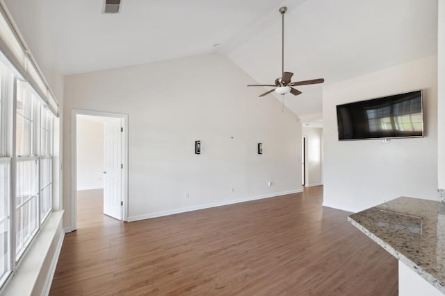 unfurnished living room with ceiling fan, wood finished floors, baseboards, and high vaulted ceiling