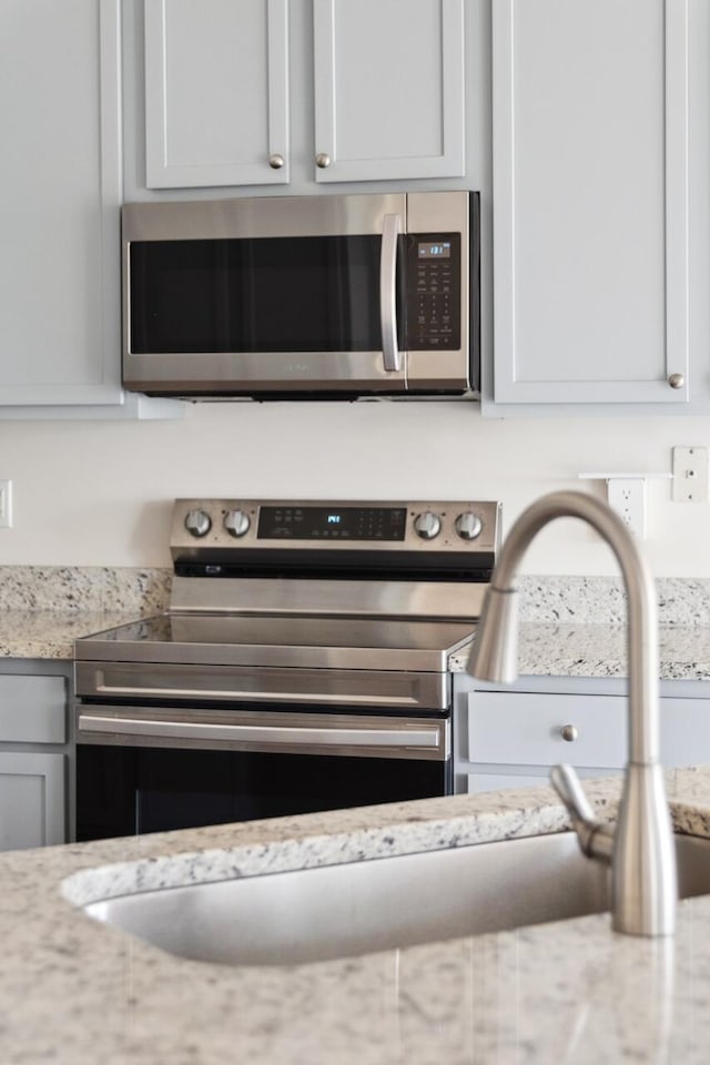 kitchen view of stainless steel appliances and light stone countertops