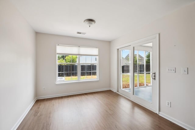 empty room featuring wood finished floors, healthy amount of natural light, and baseboards
