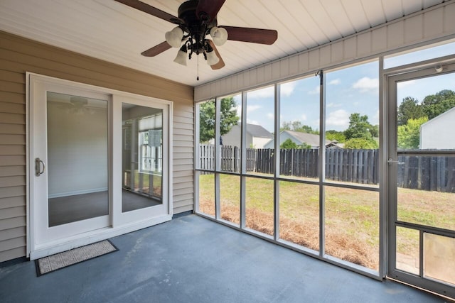 unfurnished sunroom featuring a ceiling fan and plenty of natural light