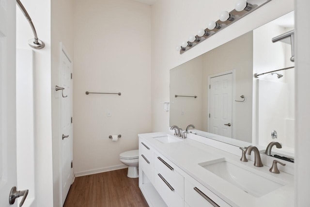 full bath with toilet, wood finished floors, baseboards, double vanity, and a shower