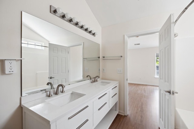 full bath with healthy amount of natural light, wood finished floors, lofted ceiling, and double vanity