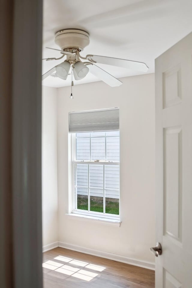 empty room with a ceiling fan, wood finished floors, and baseboards