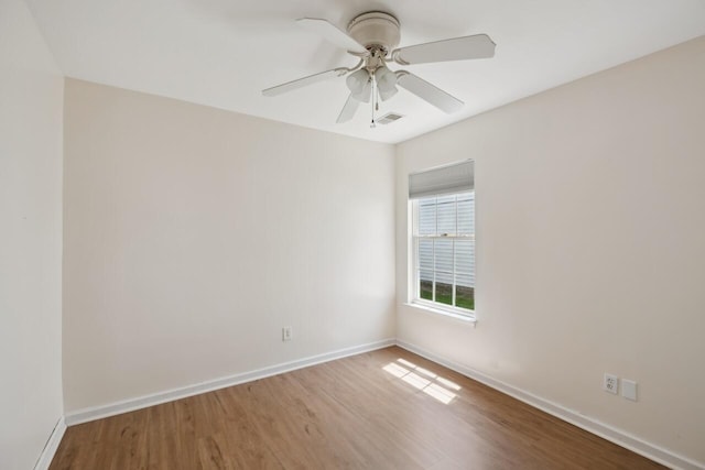 empty room with wood finished floors, baseboards, and a ceiling fan