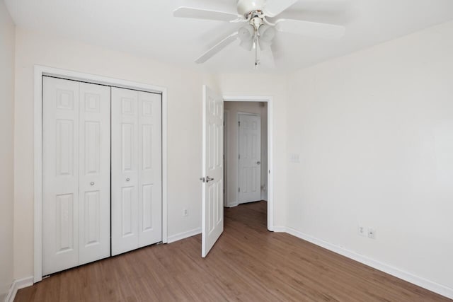 unfurnished bedroom with wood finished floors, baseboards, a closet, and ceiling fan