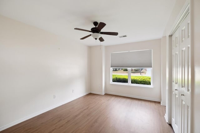 empty room with wood finished floors, baseboards, and ceiling fan