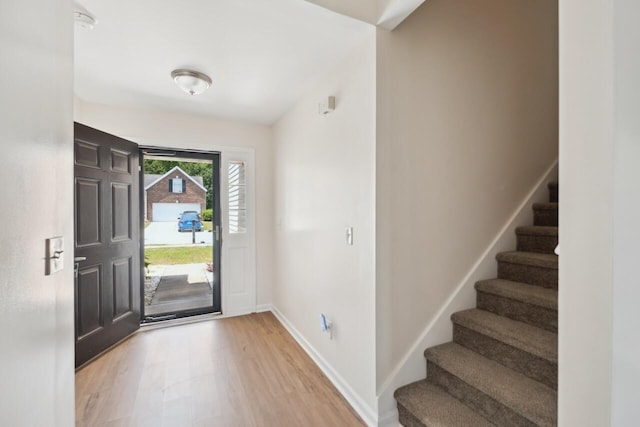 entrance foyer with light wood-style flooring, stairway, and baseboards