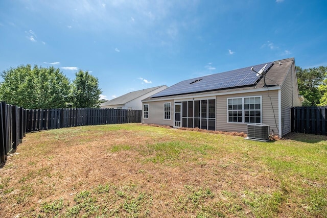 back of house with roof mounted solar panels, a sunroom, and cooling unit