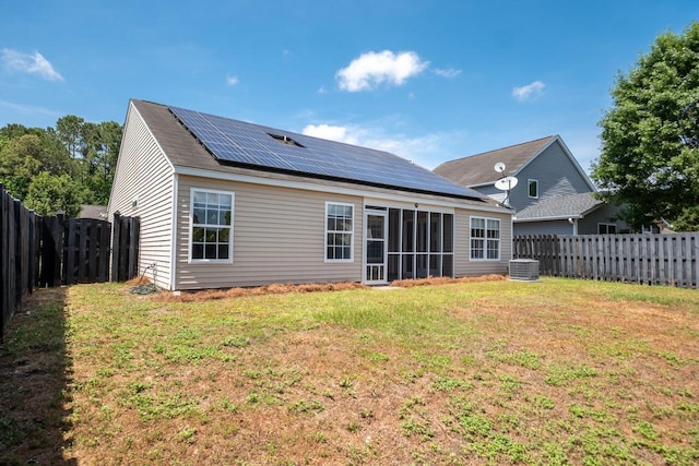 rear view of property featuring roof mounted solar panels, central air condition unit, and a sunroom